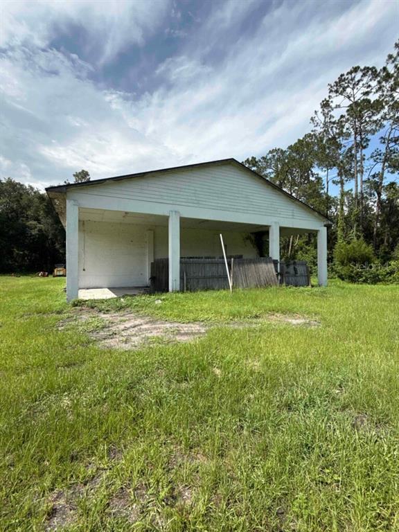 A white, open-sided pole barn structure stands in a grassy field under a cloudy sky — 1116 N HIGHWAY 17 UNIT 1, PALATKA, FL