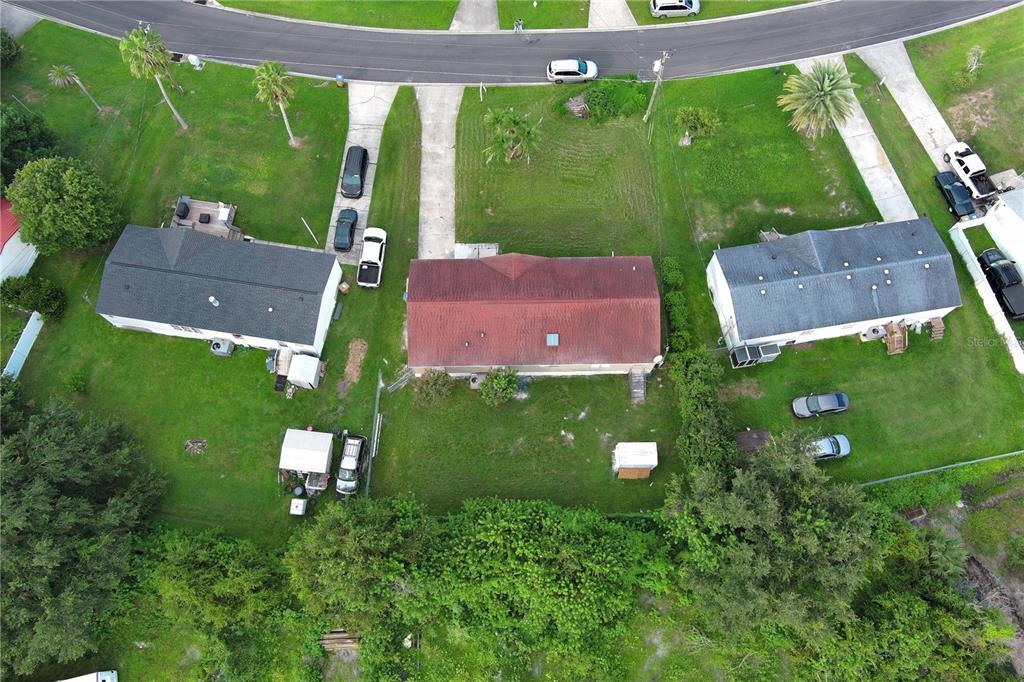 An aerial view shows three houses with driveways and backyards in a residential neighborhood — 1124 DARA CAY DRIVE, KISSIMMEE, FL