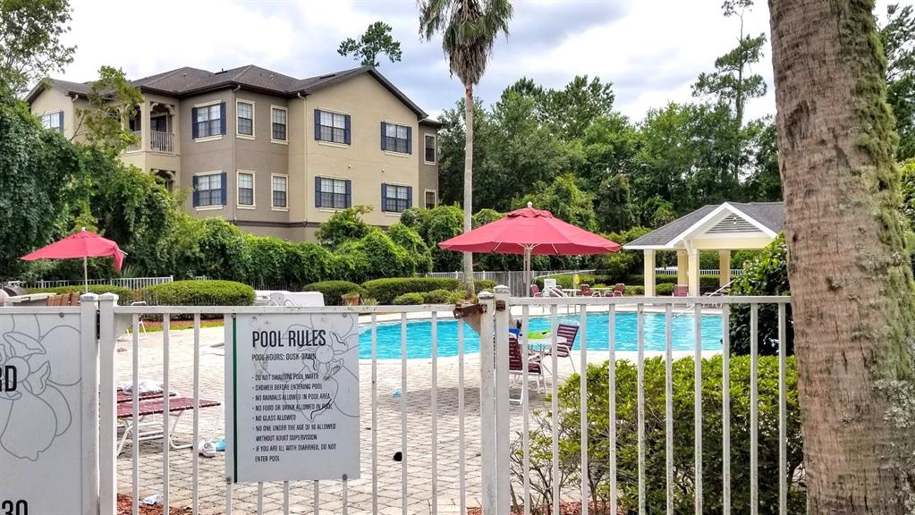 A brick entrance sign for Magnolia Place stands in front of palm trees and a building — 4335 NW 48TH STREET UNIT 105, GAINESVILLE, FL