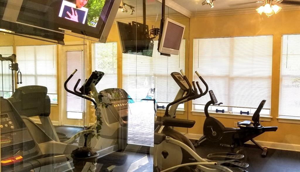 A home theater room features a large projection screen, leather seating, and tan walls — 4335 NW 48TH STREET UNIT 105, GAINESVILLE, FL