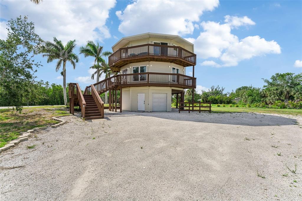 A three-story octagonal house with wraparound wooden decks stands on a gravel lot — 16361 STRINGFELLOW ROAD, BOKEELIA, FL