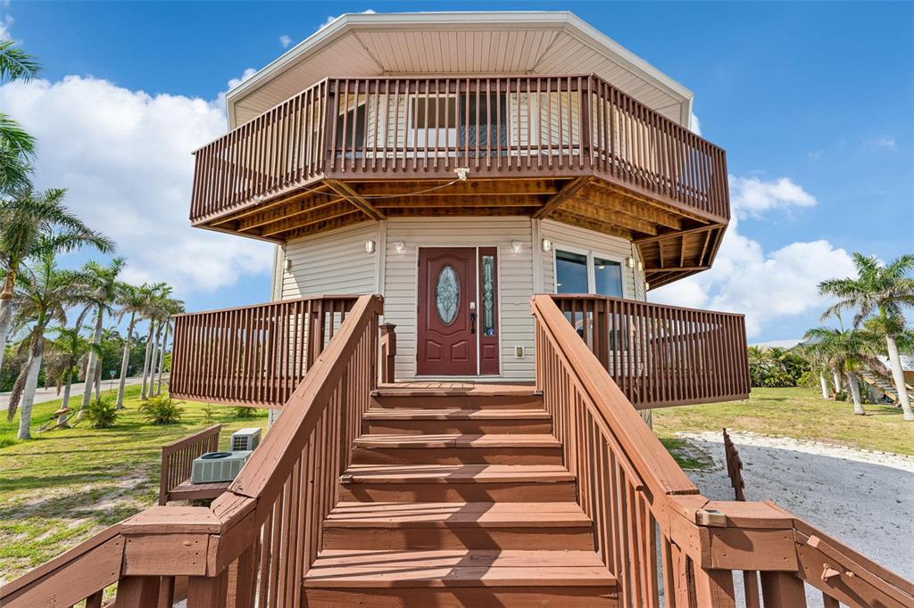 An elevated octagonal house with a wooden staircase leading to a front door and balcony — 16361 STRINGFELLOW ROAD, BOKEELIA, FL