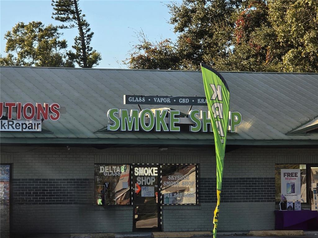 The exterior of a retail smoke shop features a green metal roof and brick walls — 3020 15TH STREET E, BRADENTON, FL