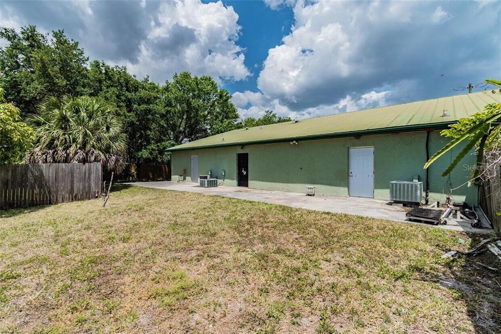 The exterior of a green building features a concrete patio and a grassy backyard — 3020 15TH STREET E, BRADENTON, FL
