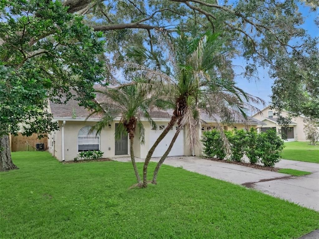 A single-story house with a beige exterior, a two-car garage, and palm trees in front — 1434 SHIRLEY DRIVE, LAKELAND, FL