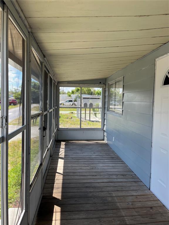 A screened-in porch features wood plank flooring, light blue siding, and a white entry door — 3731 STATE ROAD 60 E UNIT 23, LAKE WALES, FL