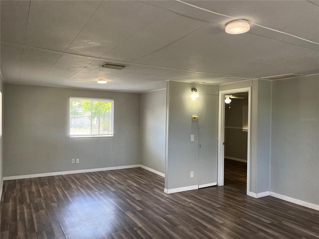A living room features gray walls, wood-look flooring, and a doorway leading to another room — 3731 STATE ROAD 60 E UNIT 23, LAKE WALES, FL