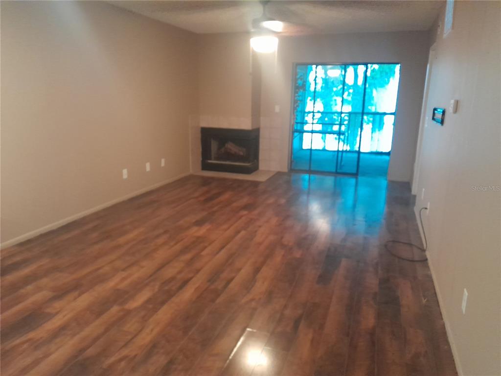 A living room with wood-look flooring, a corner fireplace, and a sliding glass door — 25210 NORTHLAKE DRIVE UNIT 210, SANFORD, FL