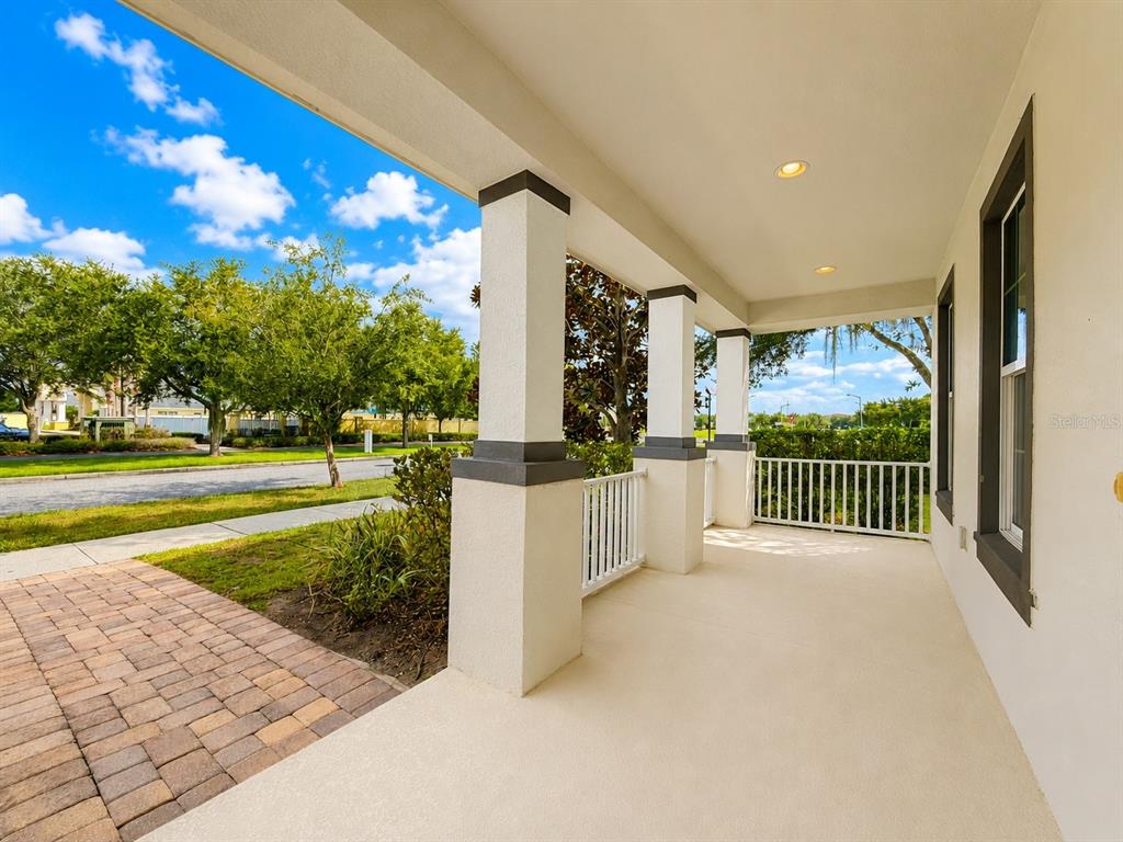 A covered porch features tan concrete flooring, white columns, and a white railing — 11804 SILVERLAKE PARK DRIVE, WINDERMERE, FL