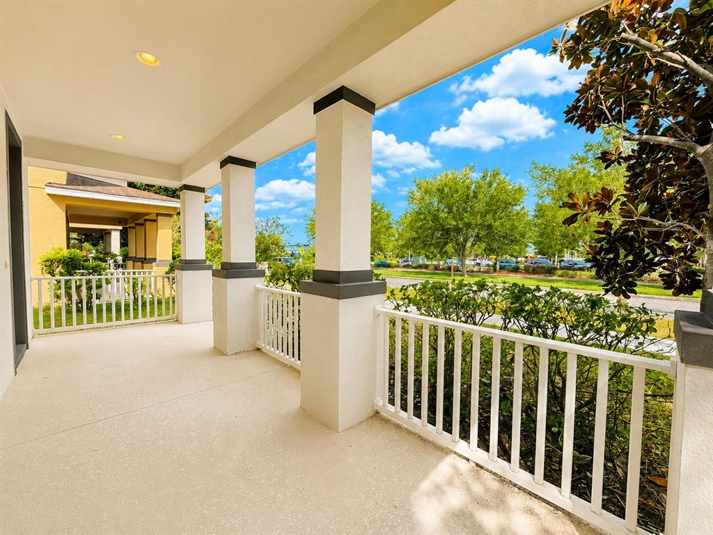 A covered porch with white railings and square columns overlooks a street and green trees — 11804 SILVERLAKE PARK DRIVE, WINDERMERE, FL