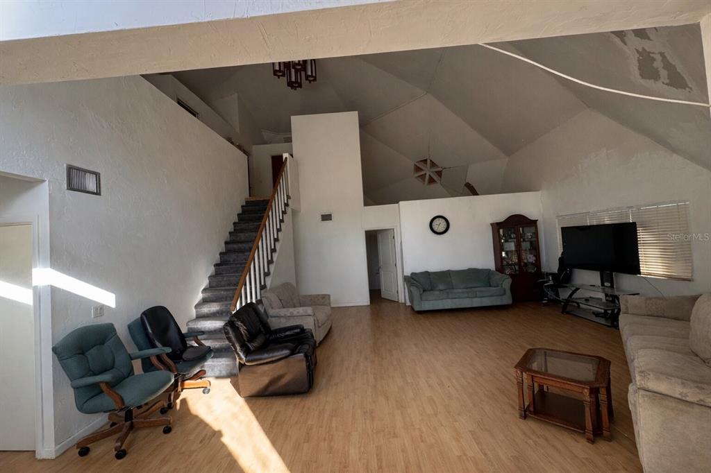 A spacious living room features vaulted ceilings, wood-look flooring, a staircase, and multiple seating areas — 7923 18TH AVENUE E, PALMETTO, FL