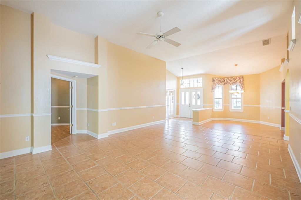 A spacious living area with tan tile floors, light yellow walls, and a ceiling fan — 7004 PINE HOLLOW DRIVE, MOUNT DORA, FL