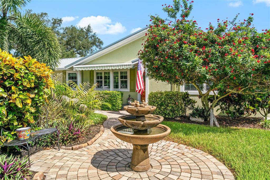 A three-tiered stone fountain sits on a circular paver patio in front of a house — 1907 MAGNOLIA STREET, SARASOTA, FL