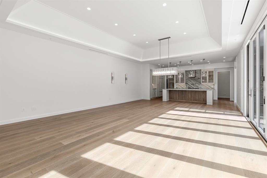 An open-concept living and dining area with neutral furniture, modern lighting, and hardwood floors — 10335 WINTER SPARKLE CIRCLE, GOLDEN OAK, FL
