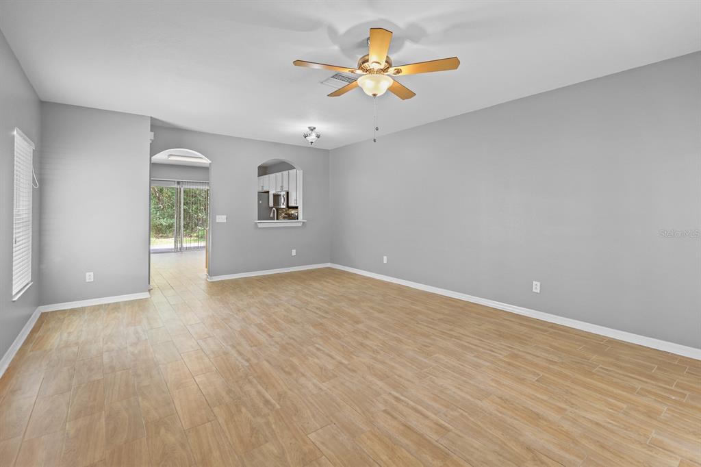 An empty room features light-colored wood-look tile flooring, gray walls, a ceiling fan, and a door — 5879 FISHHAWK RIDGE DRIVE, LITHIA, FL