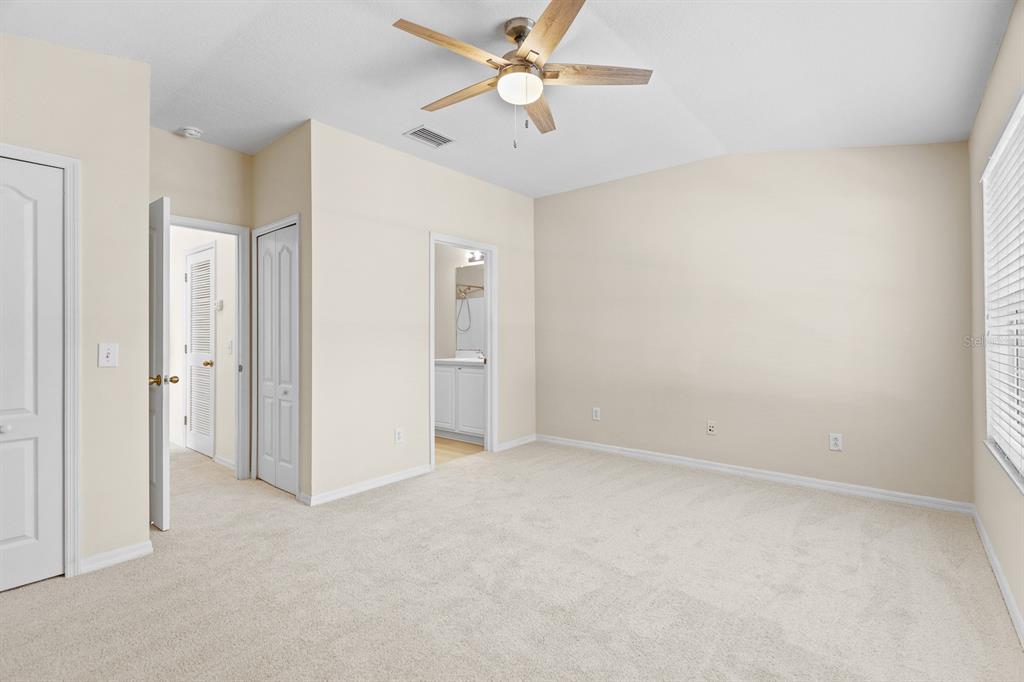 A kitchen with white cabinets, stainless steel appliances, a tiled backsplash, and light wood flooring — 5879 FISHHAWK RIDGE DRIVE, LITHIA, FL