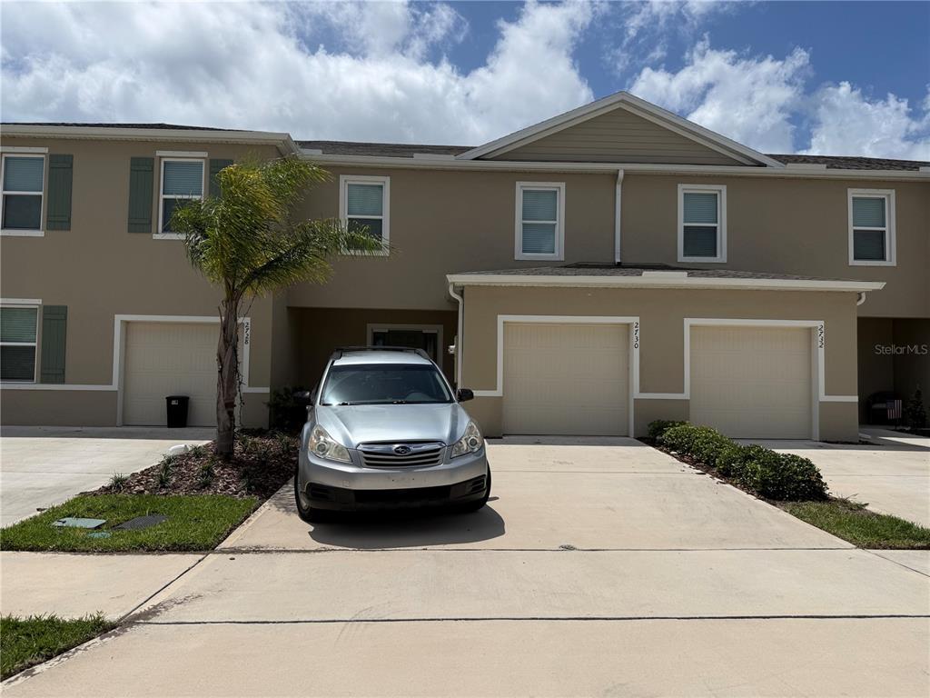 A two-story townhouse exterior features a silver car parked in front of a garage — 2730 SILVER CANOE DRIVE, EDGEWATER, FL