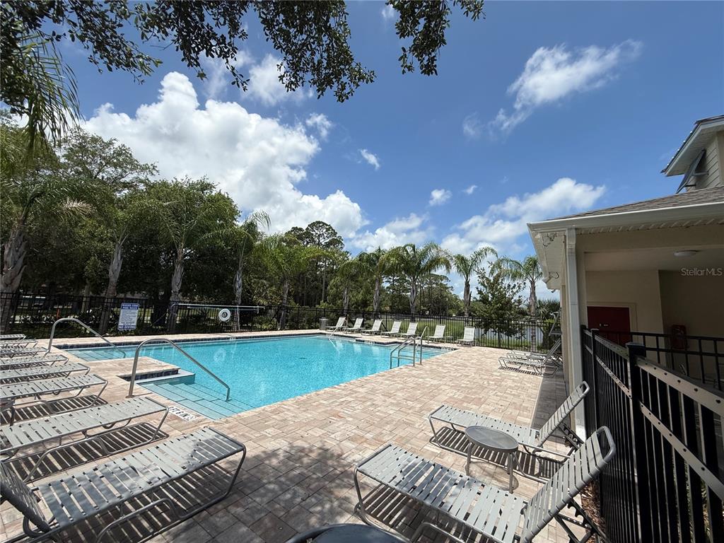 A swimming pool with lounge chairs on a paved deck under a blue sky — 2730 SILVER CANOE DRIVE, EDGEWATER, FL