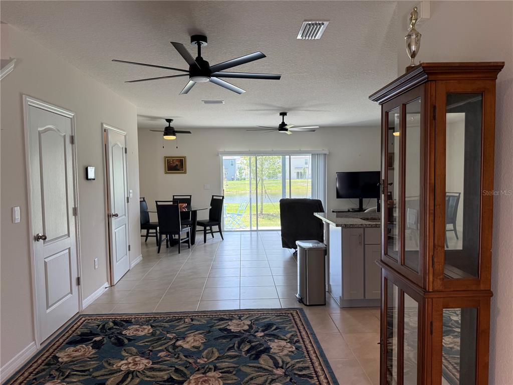 An open-concept living and dining area features tile flooring, ceiling fans, and sliding glass doors — 2730 SILVER CANOE DRIVE, EDGEWATER, FL