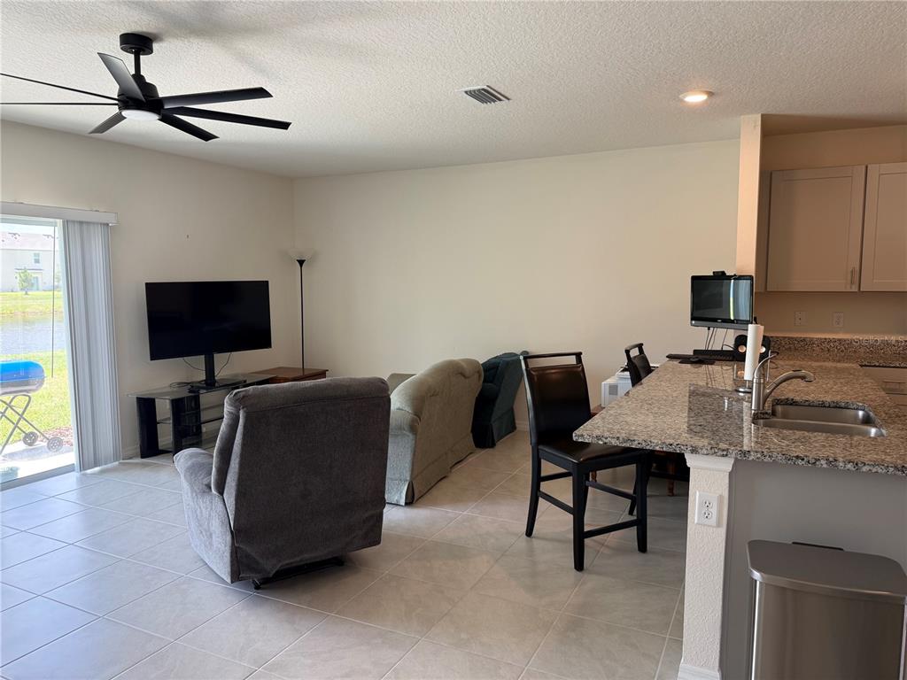 An open-concept living room features tile flooring, a ceiling fan, and a kitchen island — 2730 SILVER CANOE DRIVE, EDGEWATER, FL