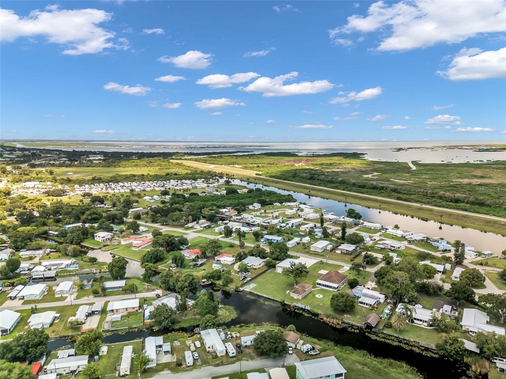 An aerial view shows a residential neighborhood with mobile homes situated along canals near a lake — 1212 9TH STREET, OKEECHOBEE, FL