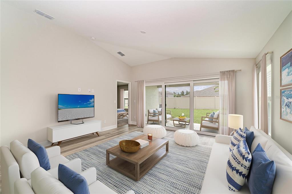 A bright living room features white sofas, a wooden coffee table, and sliding glass doors — 12361 OAK  HILL WAY, PARRISH, FL