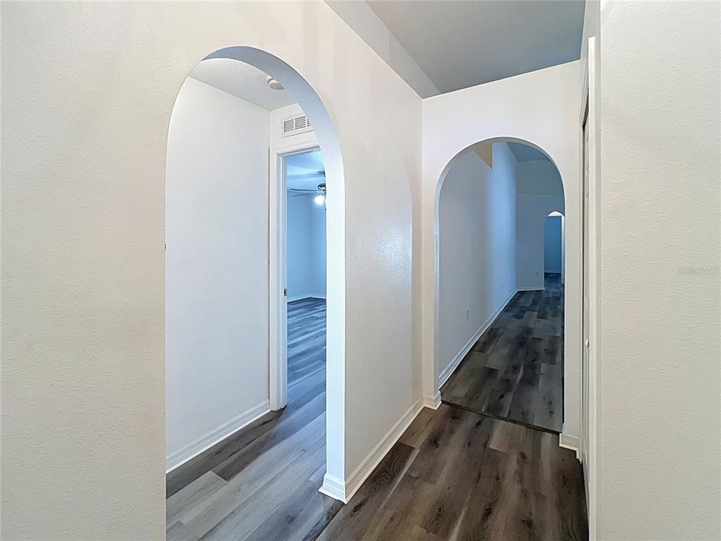 An interior hallway features two arched doorways and wood-look flooring — 5641 ROYAL HILLS DRIVE, WINTER HAVEN, FL