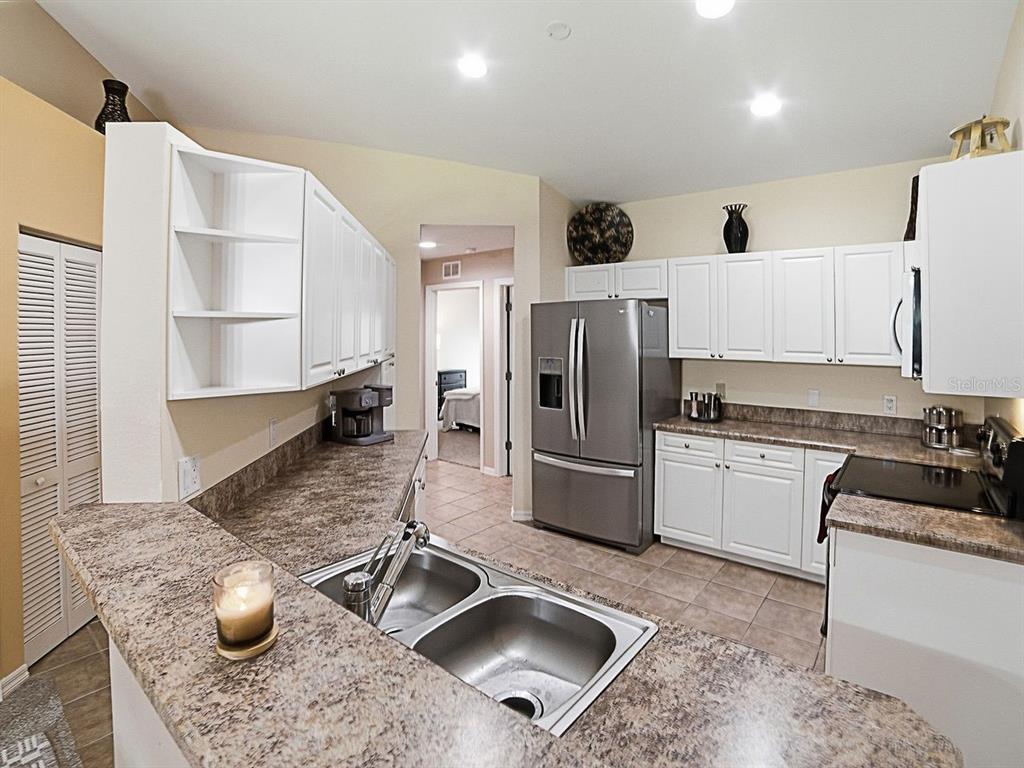 A kitchen features white cabinets, a stainless steel refrigerator, and brown laminate countertops — 5408 ADMIRAL WAY UNIT 11-202, OXFORD, FL