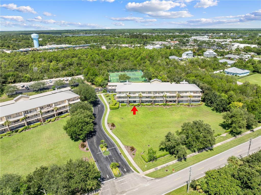 An aerial view shows two multi-story residential buildings surrounded by green lawns and trees — 13570 MYSTIC DRIVE UNIT 102, SEBASTIAN, FL