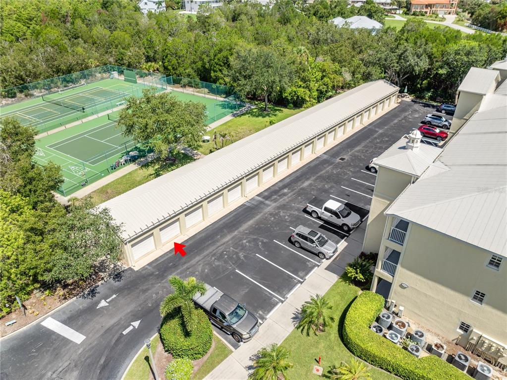 An aerial view shows a parking lot with covered carports next to tennis courts — 13570 MYSTIC DRIVE UNIT 102, SEBASTIAN, FL
