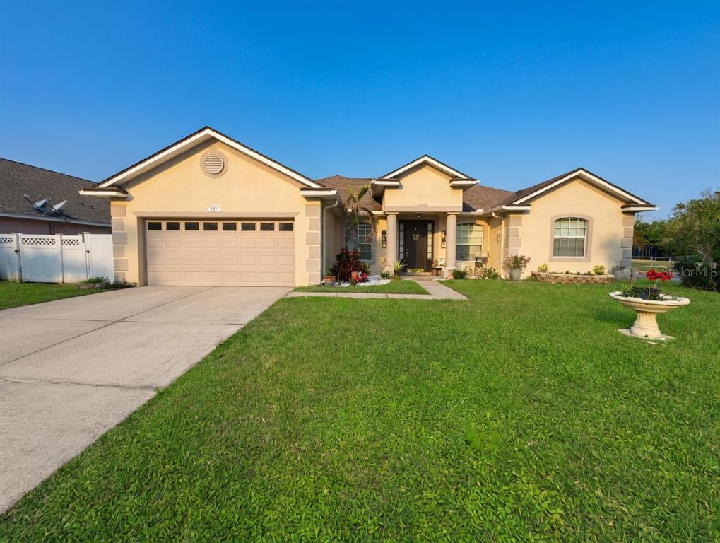 A single-story house with a tan stucco exterior, a two-car garage, and a front lawn — 2601 GOLD DUST CIRCLE, KISSIMMEE, FL
