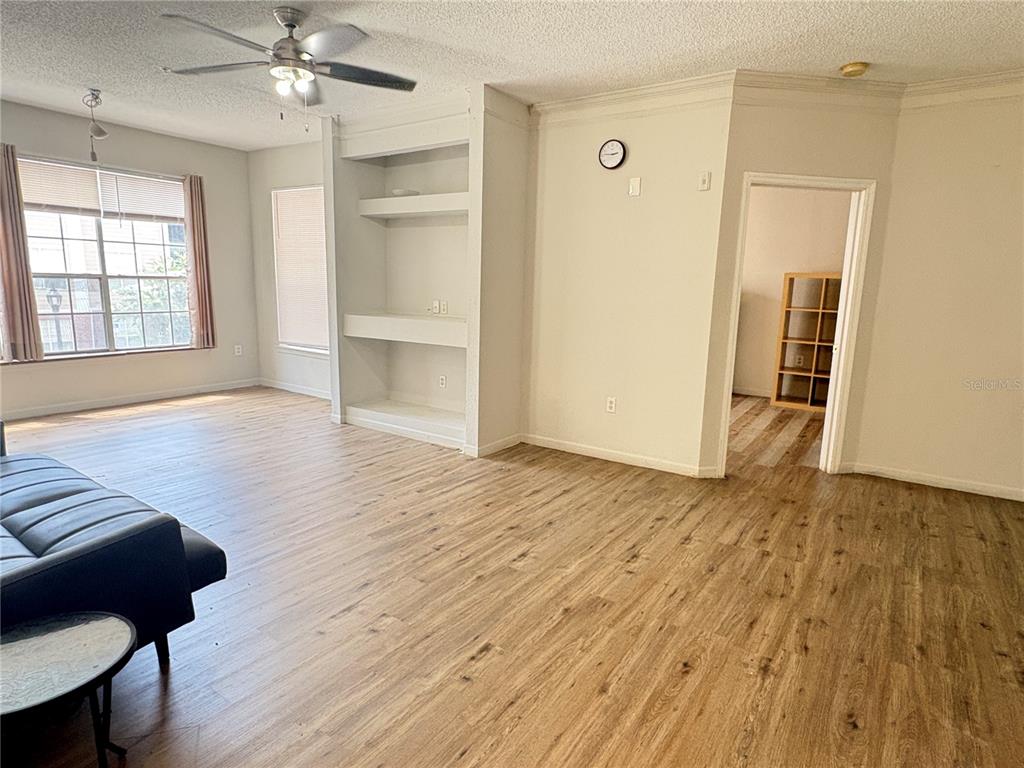 A living room features wood-look flooring, a ceiling fan, built-in shelving, and a doorway — 8301 ELM PARK DRIVE UNIT 625, ORLANDO, FL