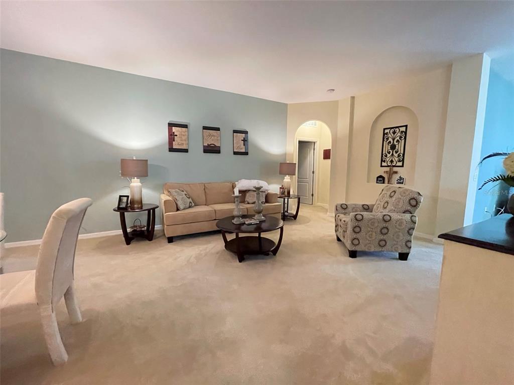 A living room features a beige sofa, a patterned armchair, and a light blue wall — 5804 DORNICH DRIVE, AUBURNDALE, FL