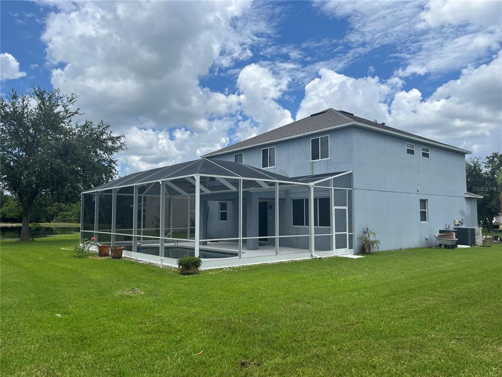 A two-story house with a screened-in pool enclosure sits on a large grassy lawn — 5966 WILLOWS BRIDGE LOOP, ELLENTON, FL