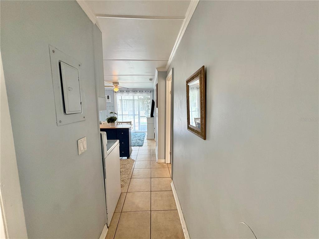 A tiled hallway leads past a kitchen toward a bright living area with sliding doors — 10301 US HIGHWAY 27 UNIT 192, CLERMONT, FL