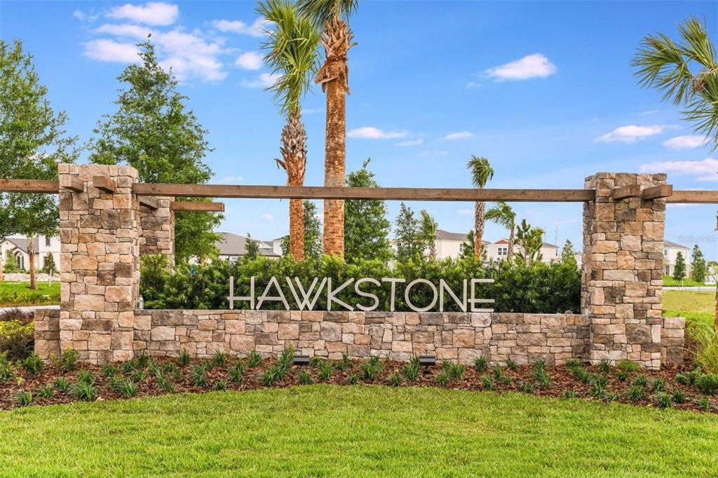 A stone monument sign for the Hawkstone community stands in front of palm trees — 14930 RIDER PASS DRIVE, LITHIA, FL