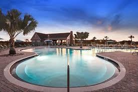 A swimming pool with a surrounding brick patio and a clubhouse in the background — 14930 RIDER PASS DRIVE, LITHIA, FL