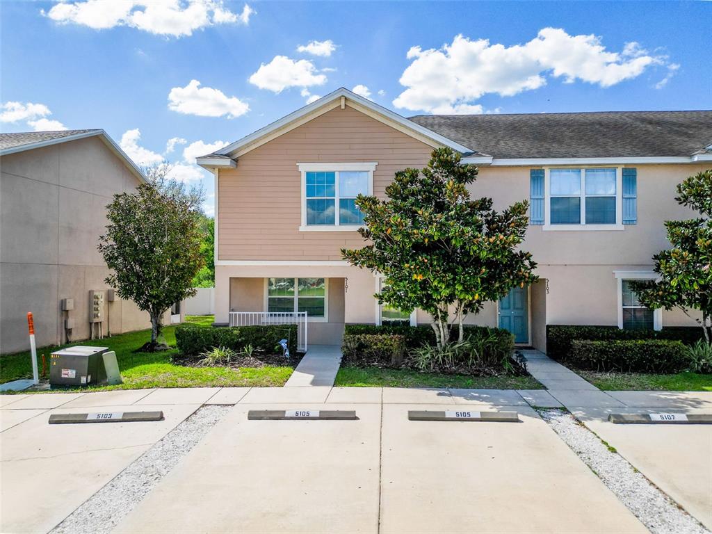 A two-story townhouse exterior features tan siding, a front walkway, and assigned parking spaces — 5101 CHIPOTLE LANE, WESLEY CHAPEL, FL