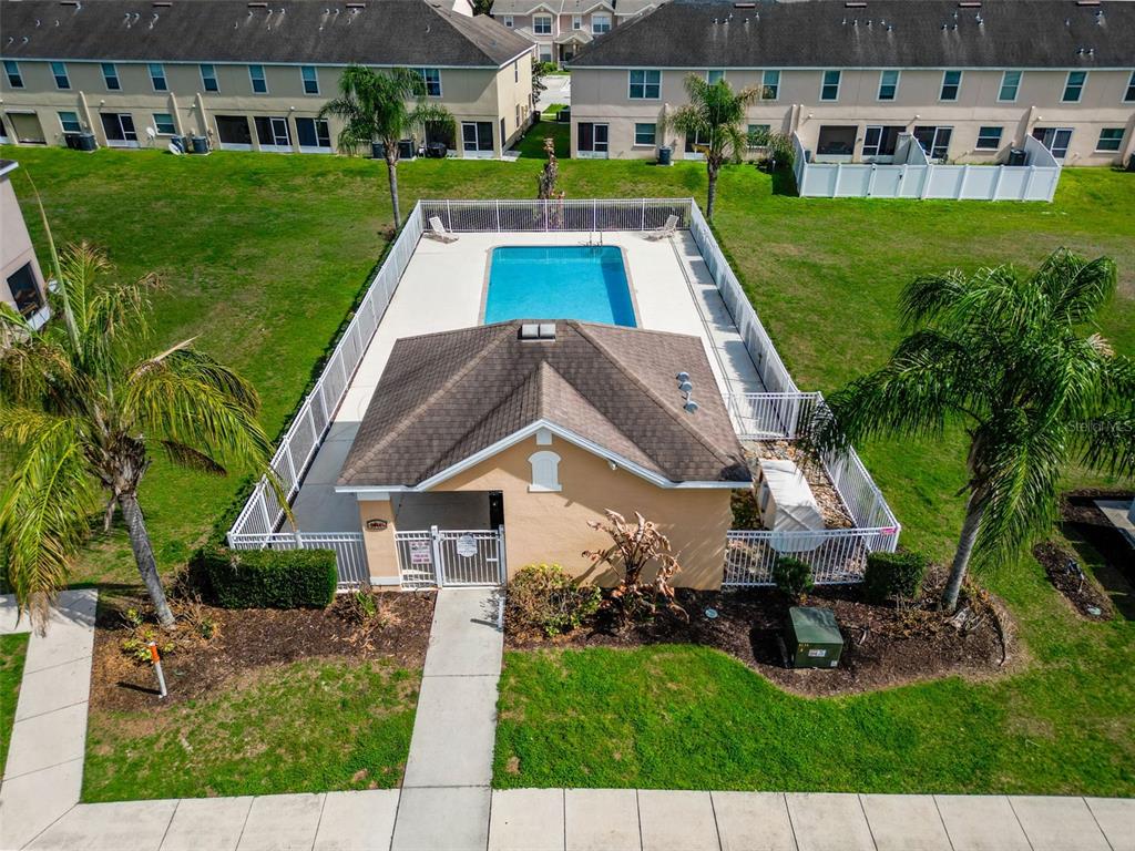 An aerial view of a community swimming pool area with a clubhouse and palm trees — 5101 CHIPOTLE LANE, WESLEY CHAPEL, FL