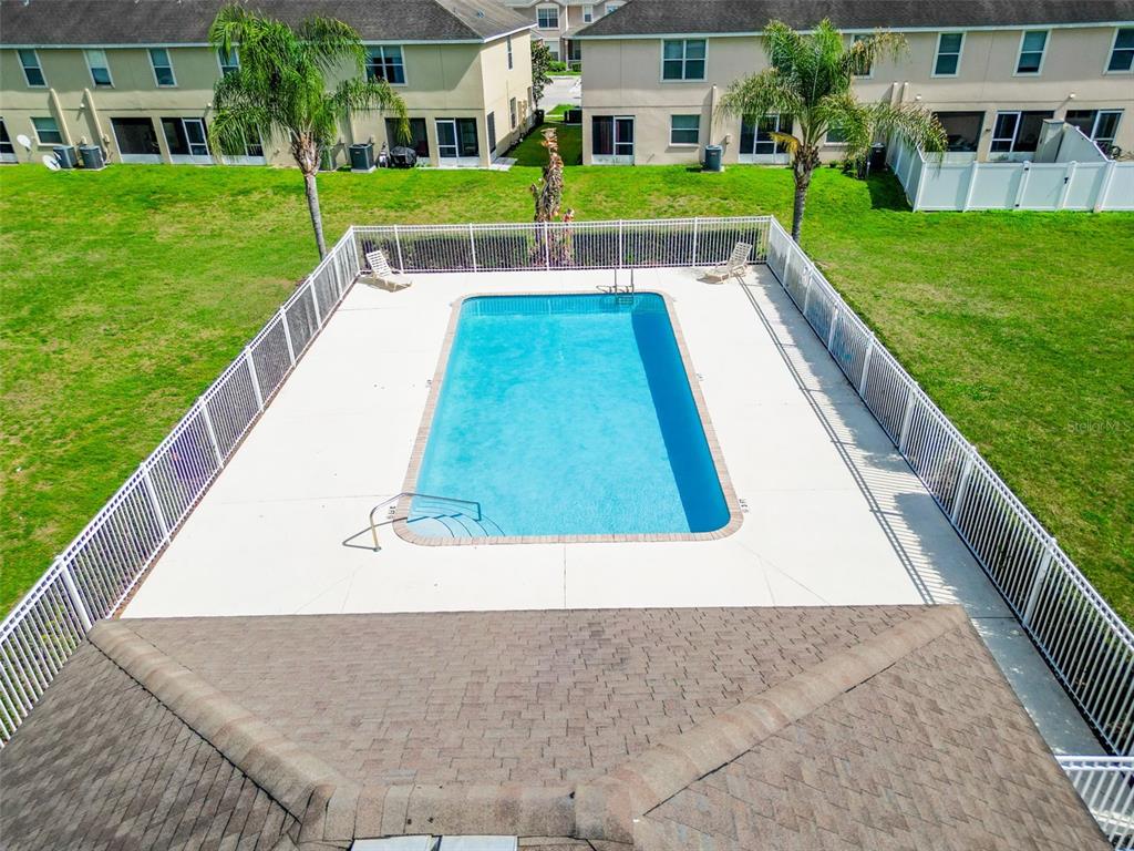 An aerial view shows a rectangular swimming pool enclosed by a white fence in a backyard — 5101 CHIPOTLE LANE, WESLEY CHAPEL, FL