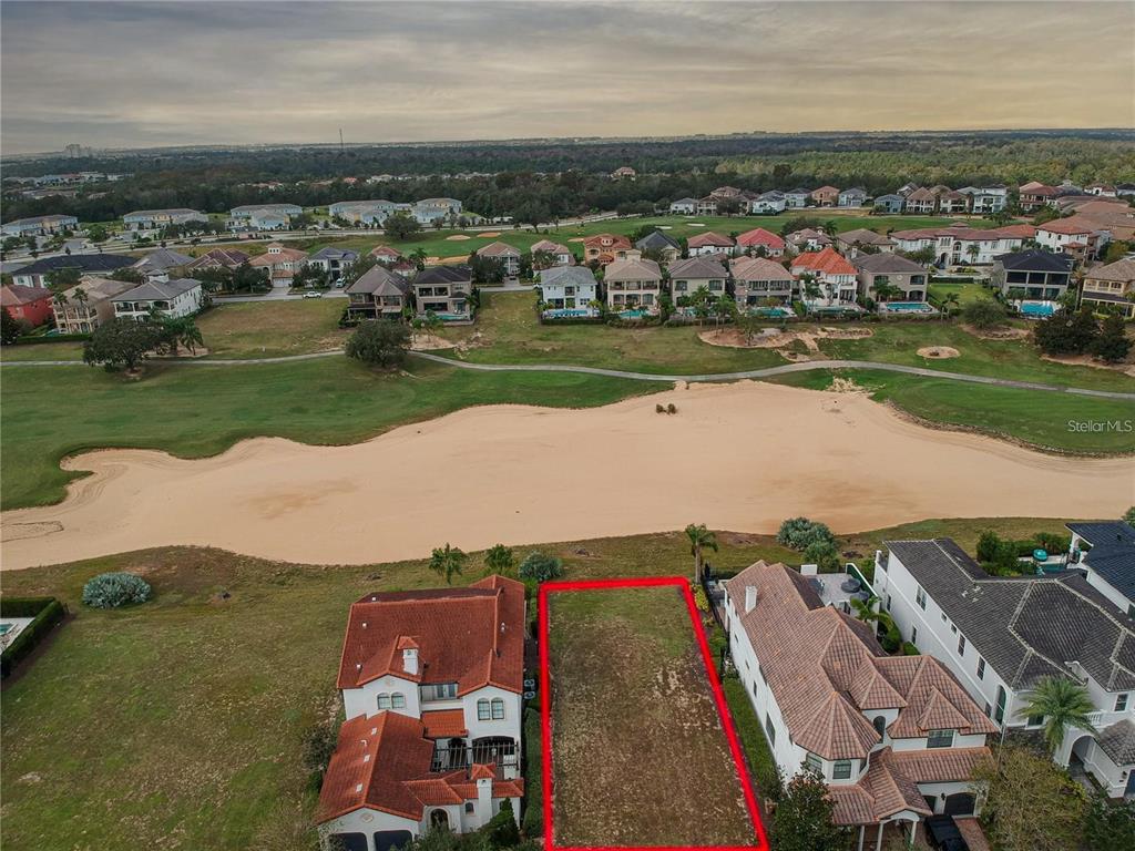 An aerial view shows a vacant residential lot outlined in red between two large houses — 541 MUIRFIELD LOOP, REUNION, FL