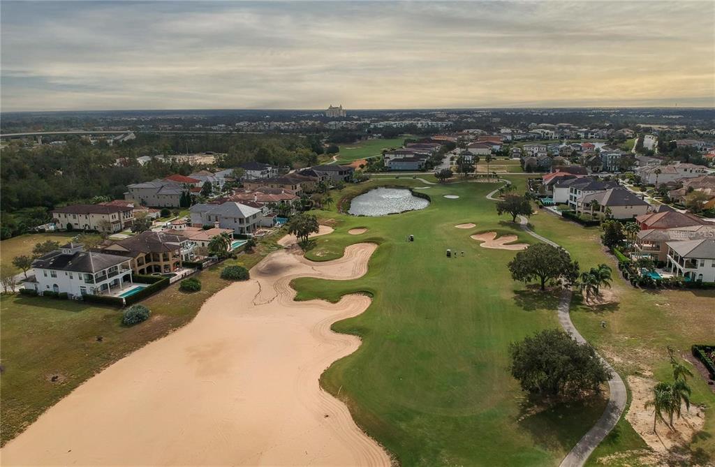 An aerial view of a golf course fairway surrounded by residential houses and a pond — 541 MUIRFIELD LOOP, REUNION, FL