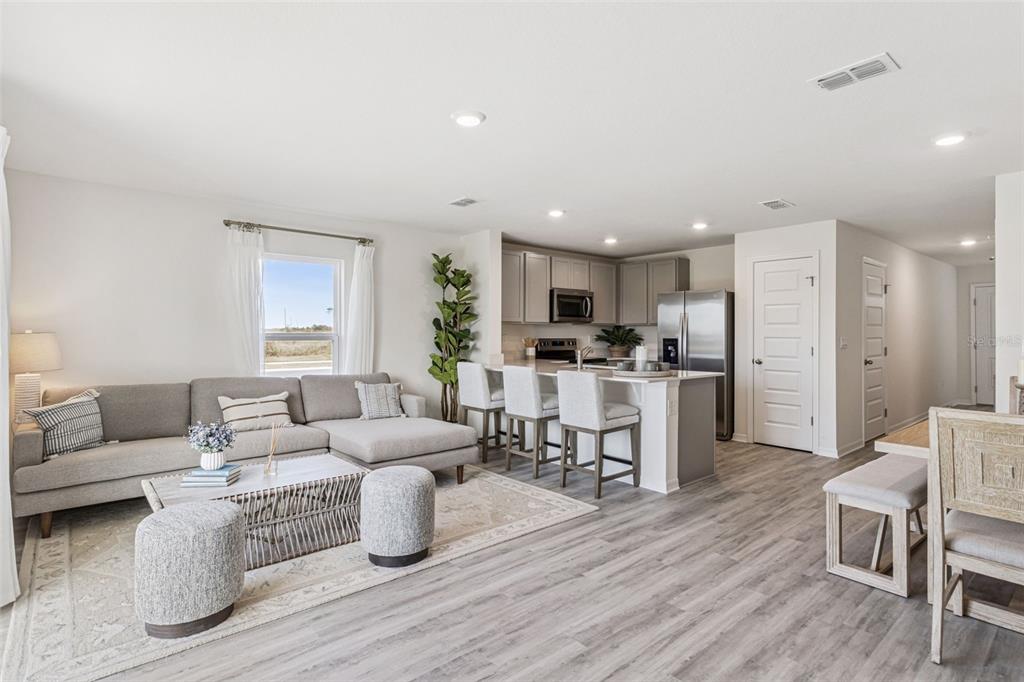 An open-concept living room and kitchen featuring light wood flooring, a sectional sofa, and island seating — 4714 TONY STREET, LAKE WALES, FL