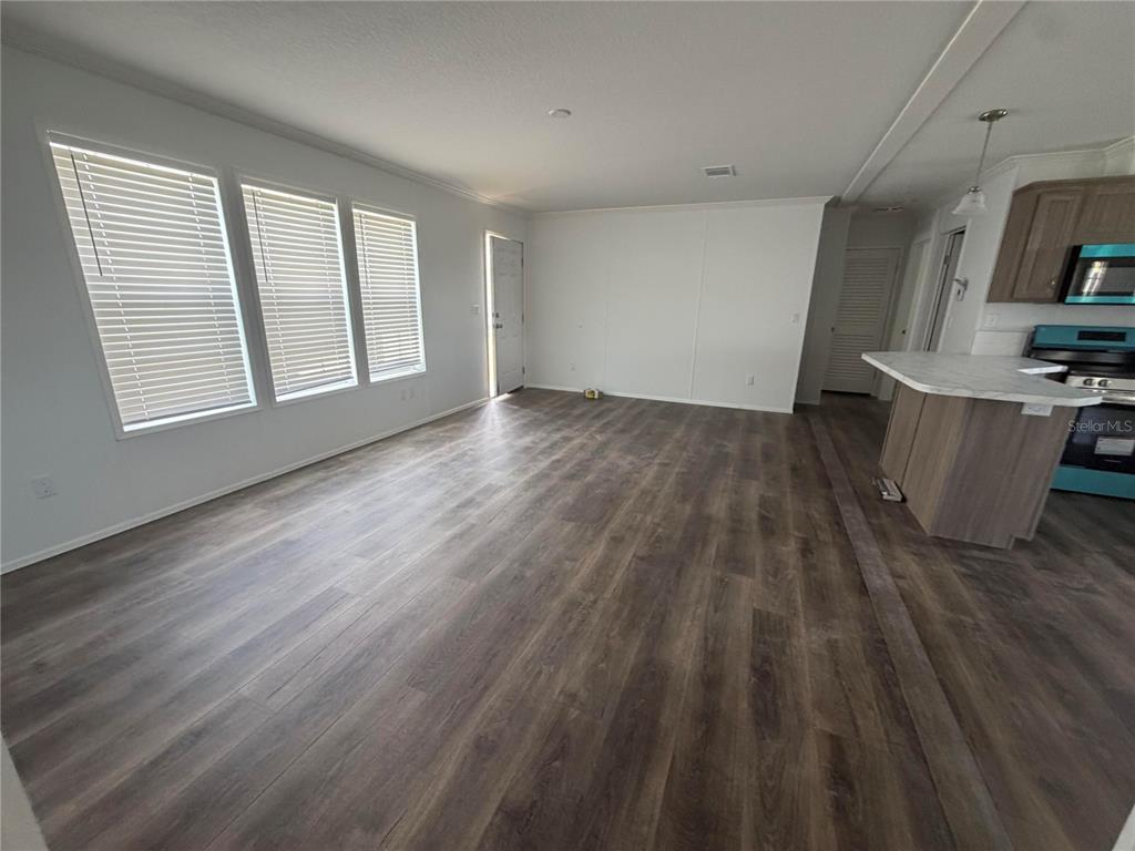 An open-concept living area features wood-look flooring, white walls, and an adjacent kitchen island — 19983 NW 242ND STREET, OKEECHOBEE, FL