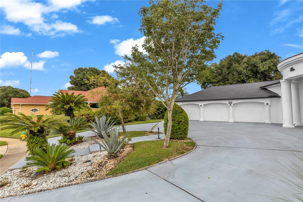 A three-car garage with a paved driveway and landscaped front yard under a blue sky — 417 GREENRIDGE COURT, DEBARY, FL