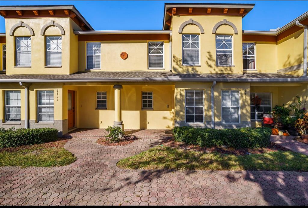 The exterior of a yellow two-story home features a paved walkway and a front porch — 3869 ISLAND WAY, ST PETERSBURG, FL