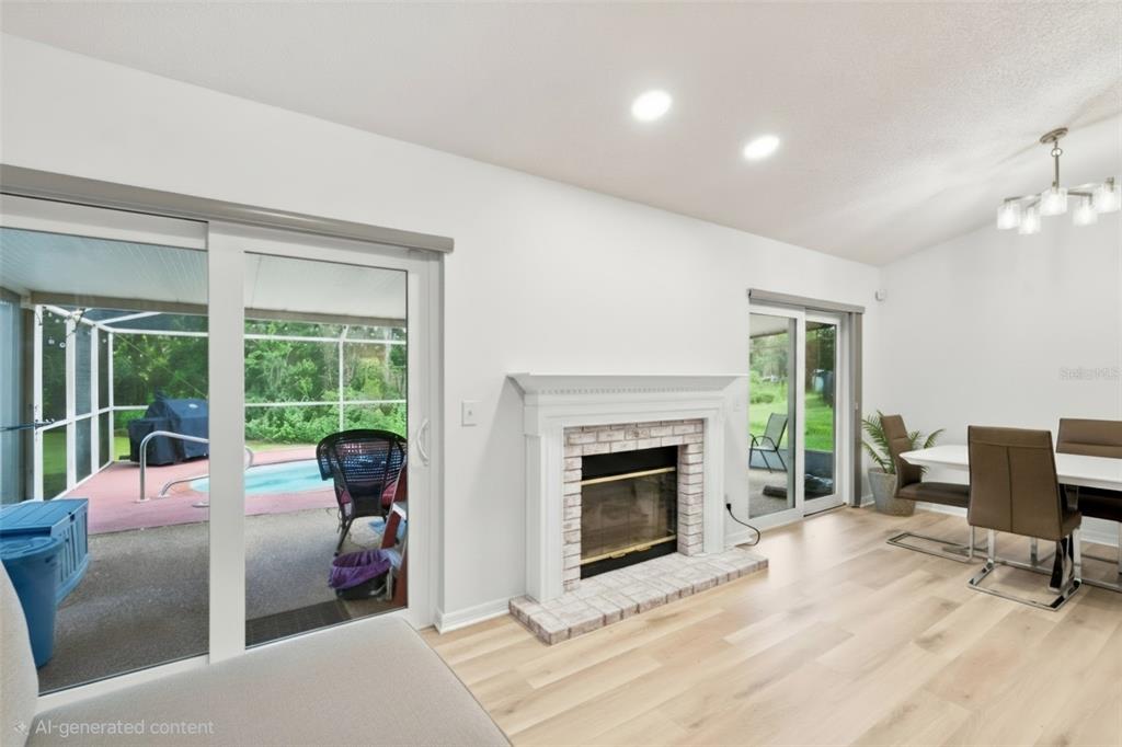 This living room features a brick fireplace, light wood flooring, and sliding doors to a pool — 1014 HARDWOOD DRIVE, VALRICO, FL