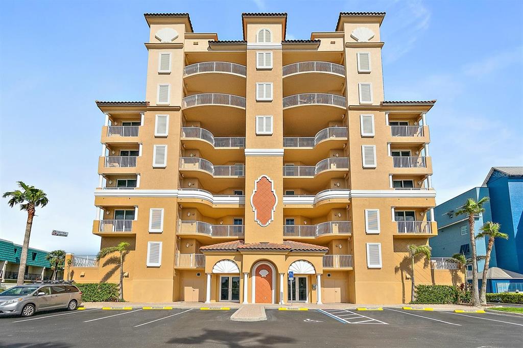 An outdoor swimming pool with a paved deck is surrounded by a fence and palm trees — 711 S ATLANTIC AVENUE Unit 202, NEW SMYRNA BEACH, FL