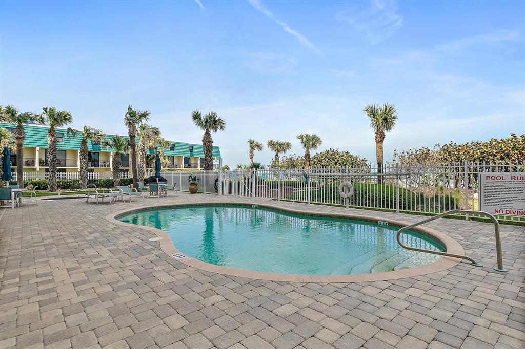 A circular hot tub sits on a paved patio next to a swimming pool — 711 S ATLANTIC AVENUE Unit 202, NEW SMYRNA BEACH, FL
