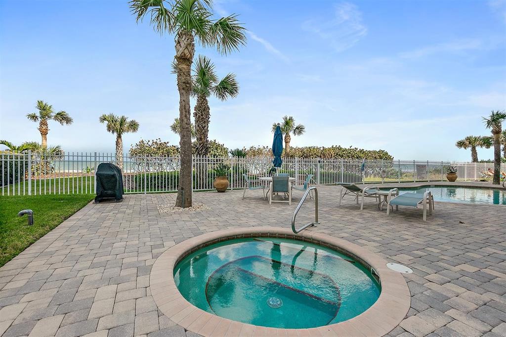 A spacious balcony features wicker furniture, sliding glass doors, and a beige exterior wall — 711 S ATLANTIC AVENUE Unit 202, NEW SMYRNA BEACH, FL